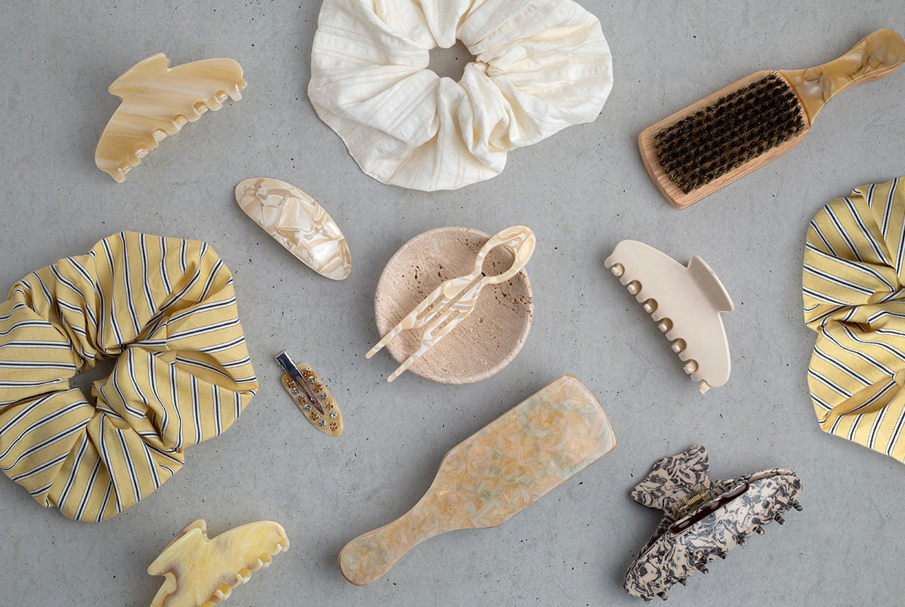 Collection of THOC hair care products including scrunchies, travel brushes, hair clips and claw clips on a grey background