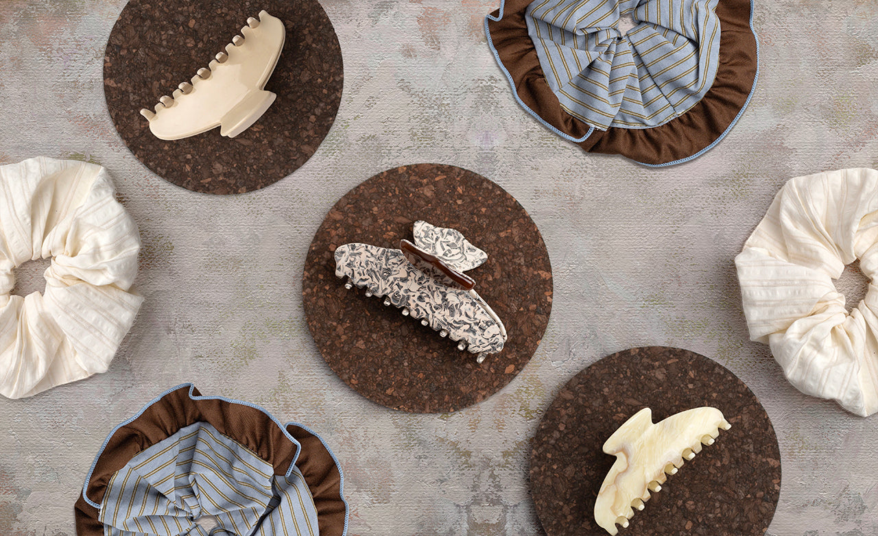 Various claw clips and scrunchies on round cork mats with a textured surface.