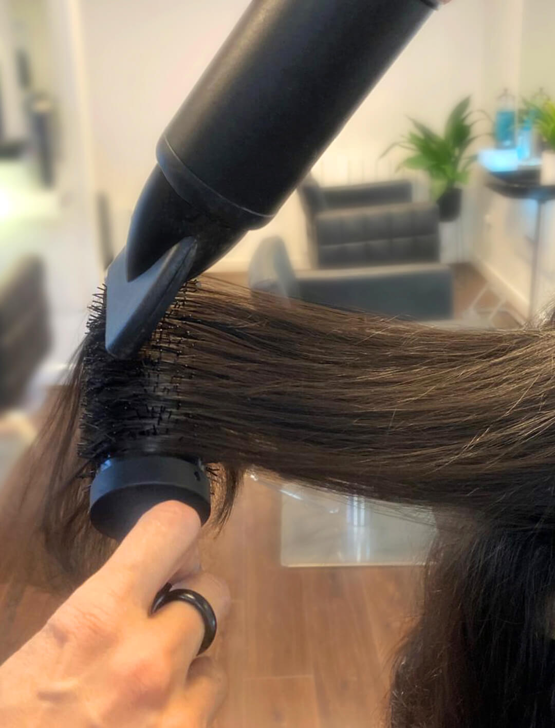 THOC founder's hands using a hair dryer with a brush on a client's hair in their setting.