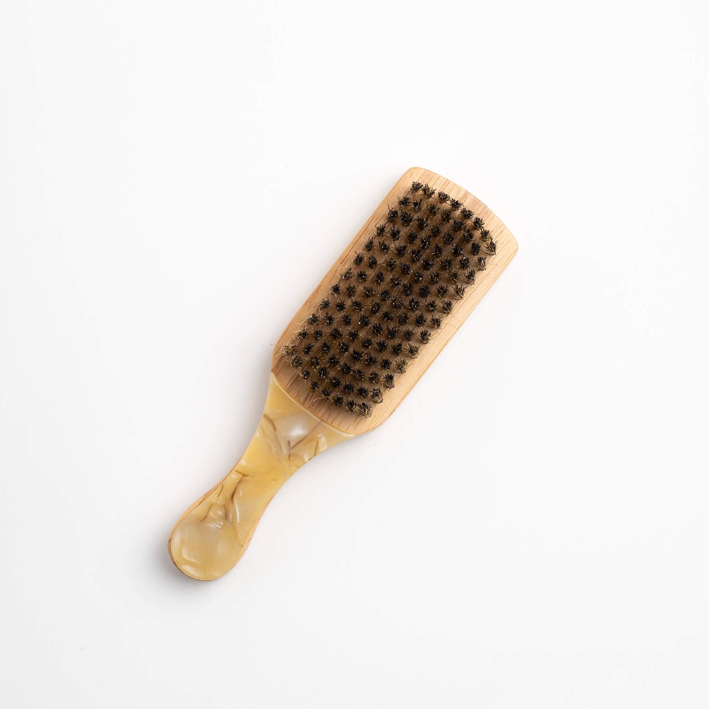 THOC Lulu Travel Brush Cream Swirl with a multi-coloured purple handle, laying handle down with boar bristles up, on a white background