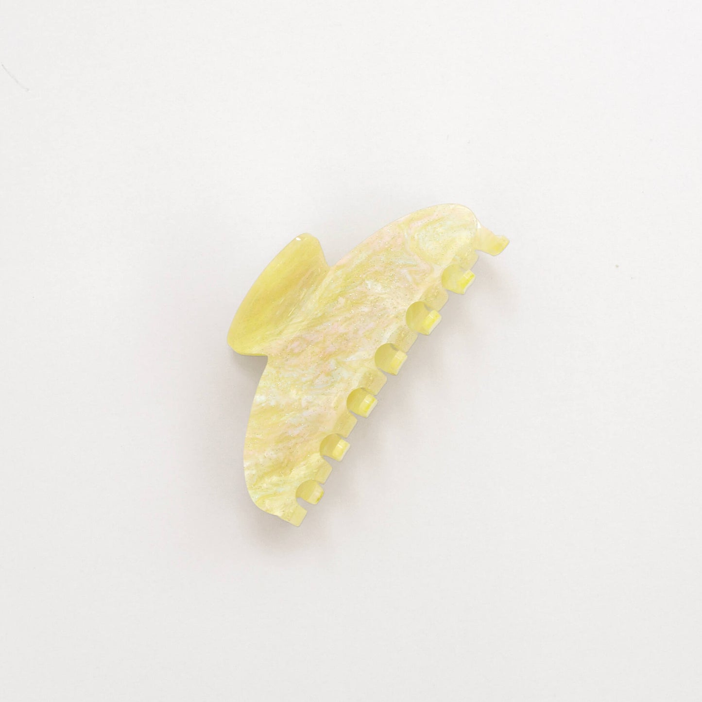 A pale yellow marble and sparkly hair claw clip with a subtle pearlescent finish, photographed on a clean white background.