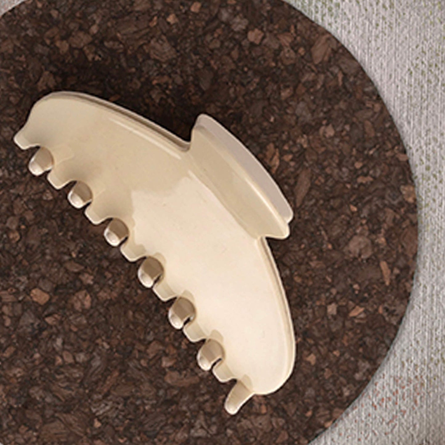 Giselle Claw Clip Vanilla Shake on a round cork mat with a textured surface.