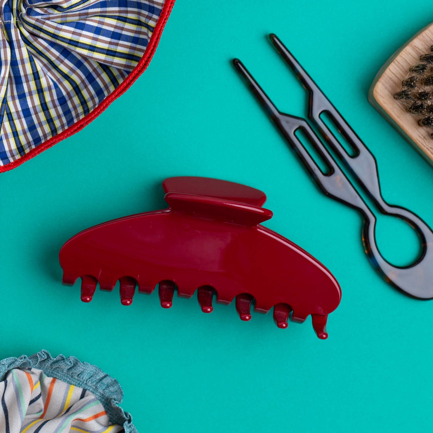 THOC Sloane Claw Clip Red Velvet with hair pin, travel brush and scrunchies, on a jade green background