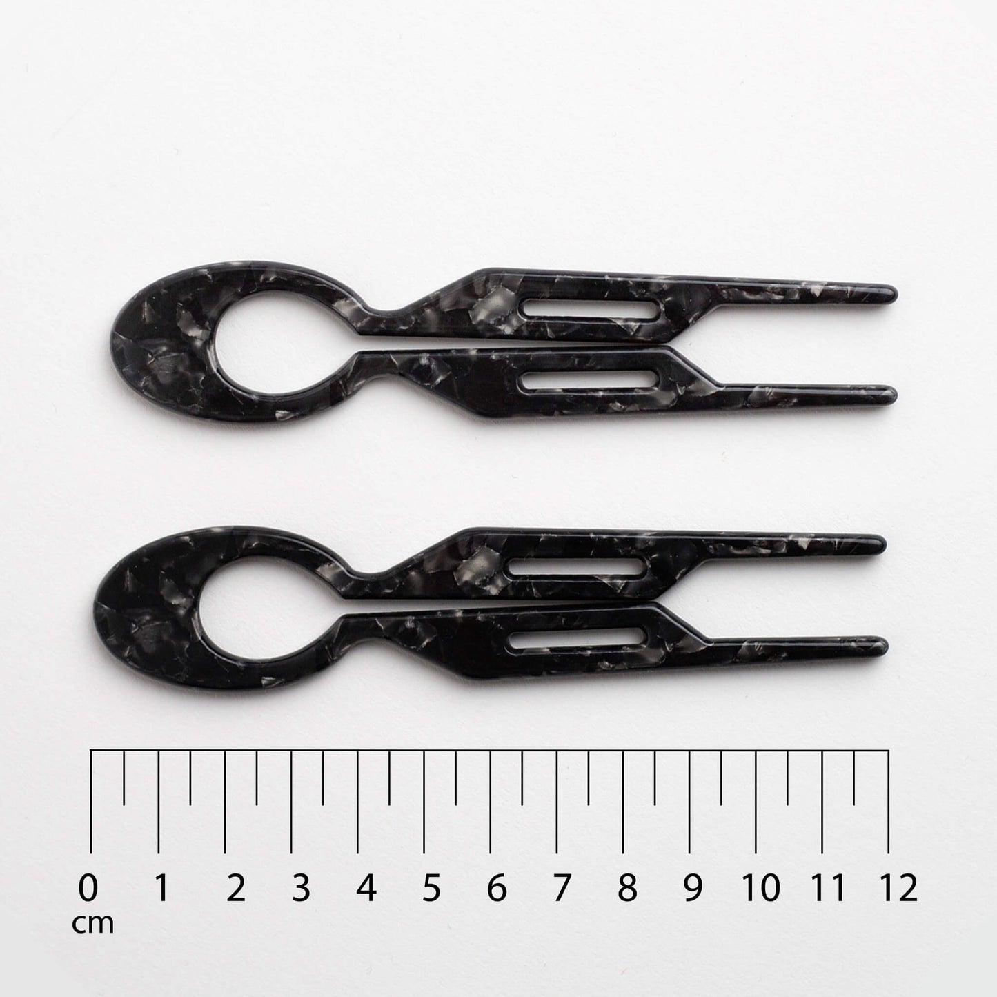 Two Camille Hair Pin Black Coffee with a ruler for scale on a white background