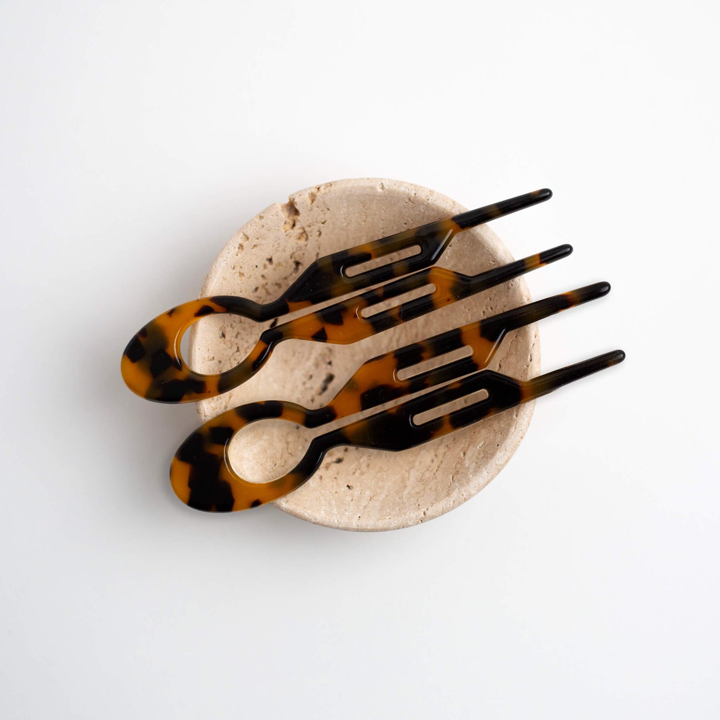 Two THOC Camille Hair Pins Brown Sugar on a cream natural stone dish on a white background