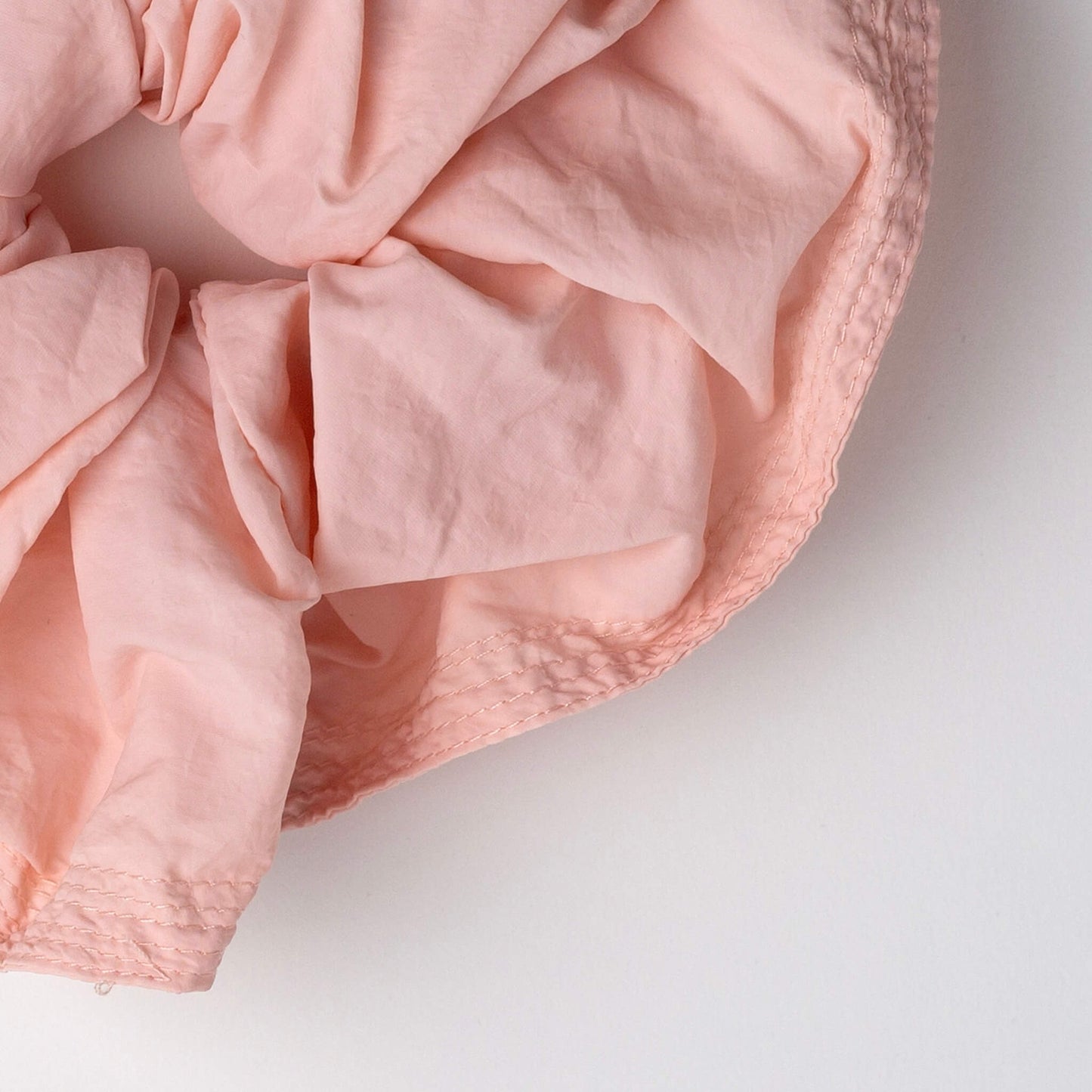 Close up of THOC Blush Scrunchie in Peach Melba colour shown on a white background