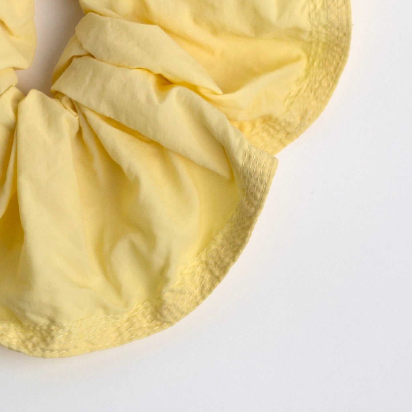 Close up of THOC Blush Scrunchie in Lemon Sherbet colour shown on a white background