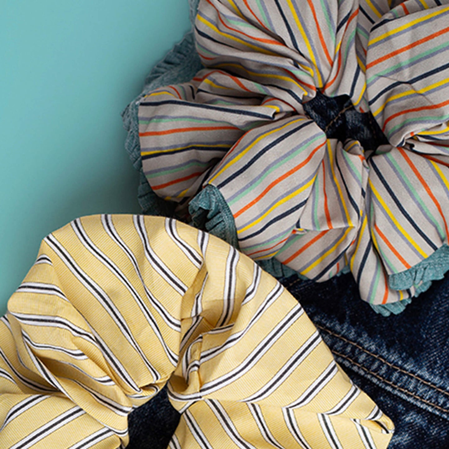 THOC Bloom and THOC Blush scrunchies resting on a denim jacket on a jade green background